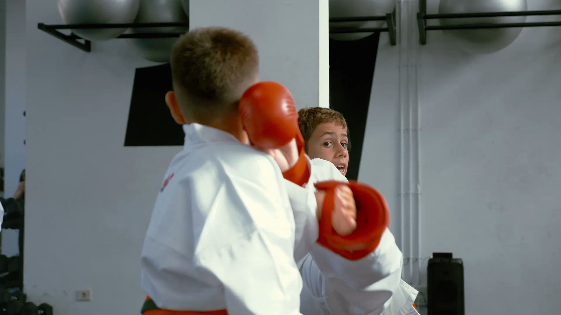 Alumnos infantiles practicando kumite con guantes en el dojo